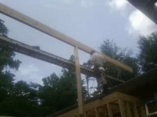 Carpenter setting a ridge beam over a new addition frame — Ice Dam Removal by Roofing Brothers in Davison