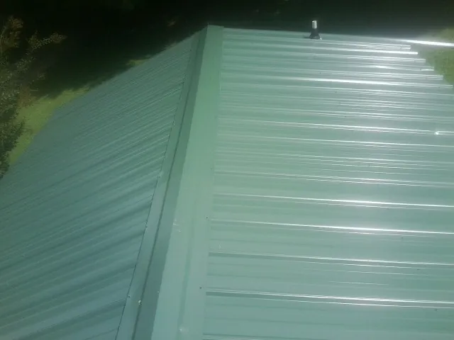 New green metal panels meeting at the ridge of a roof — Flat Roof Repair work by our crew in Davison