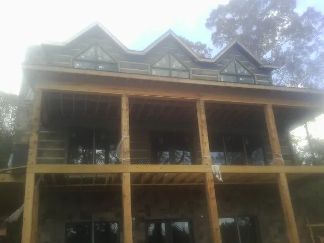 Dormers and porch framing on a large log home under construction — Roof Coating work by our crew in Davison