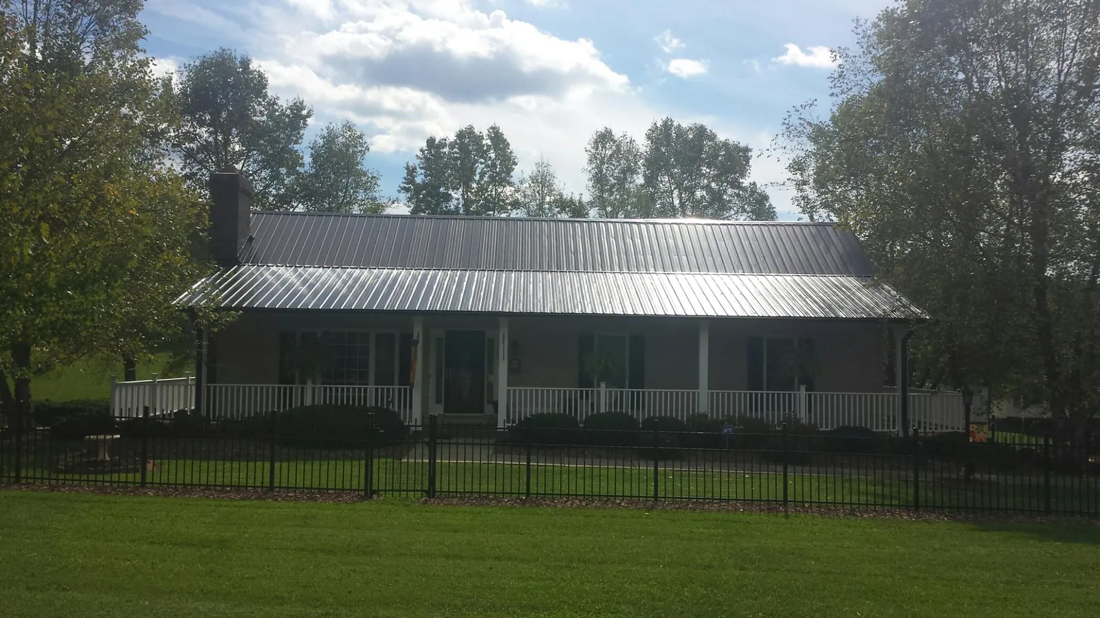 Gray metal roof on a brick ranch with a full width front porch — Gutter Guard Installation work by our crew in Davison