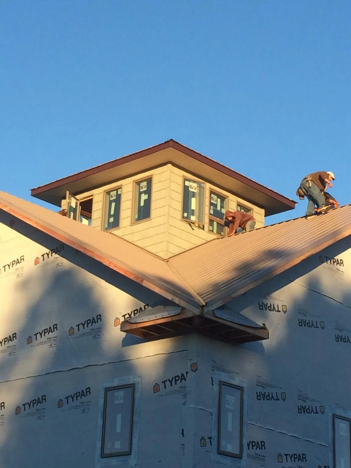 Roofers working around a rooftop cupola on a new metal roof at sunset — Roof Waterproofing in Davison by Roofing Brothers